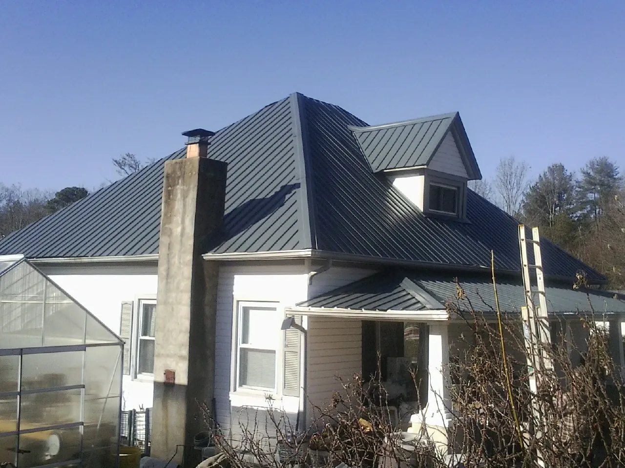 Dark blue standing seam metal roof on a white farmhouse with dormer — Slate & Tile Roof Repair by Roofing Brothers in Monponsett