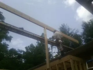 Carpenter setting a ridge beam over a new addition frame — Ice Dam Removal by Roofing Brothers in Monponsett