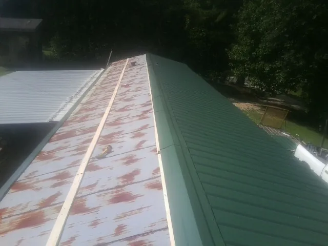 Old rusted panels beside newly installed green metal roofing — Wind Damage Roof Repair by Roofing Brothers in Monponsett