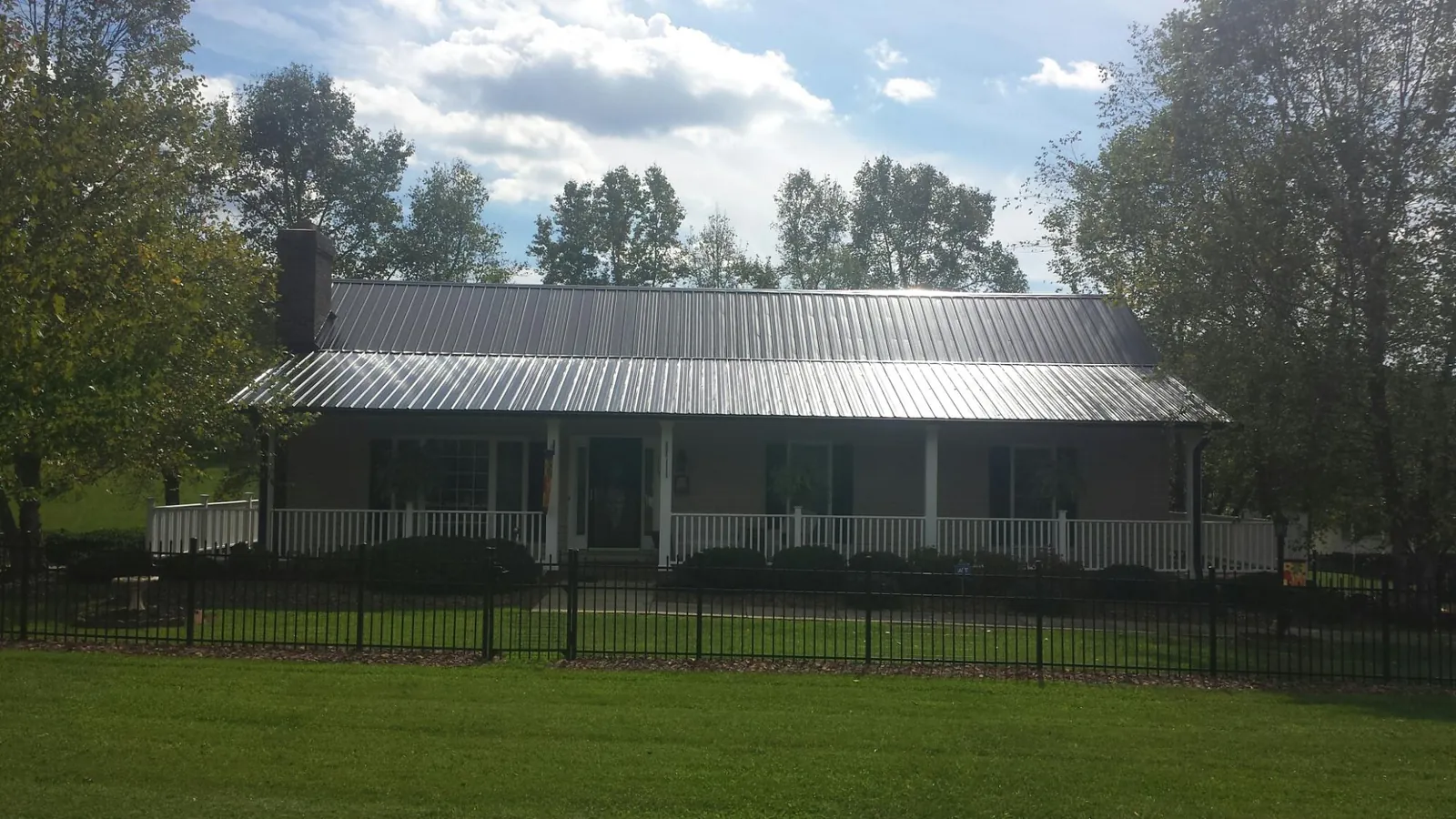 Gray metal roof on a brick ranch with a full width front porch — Gutter Guard Installation work by our crew in Monponsett