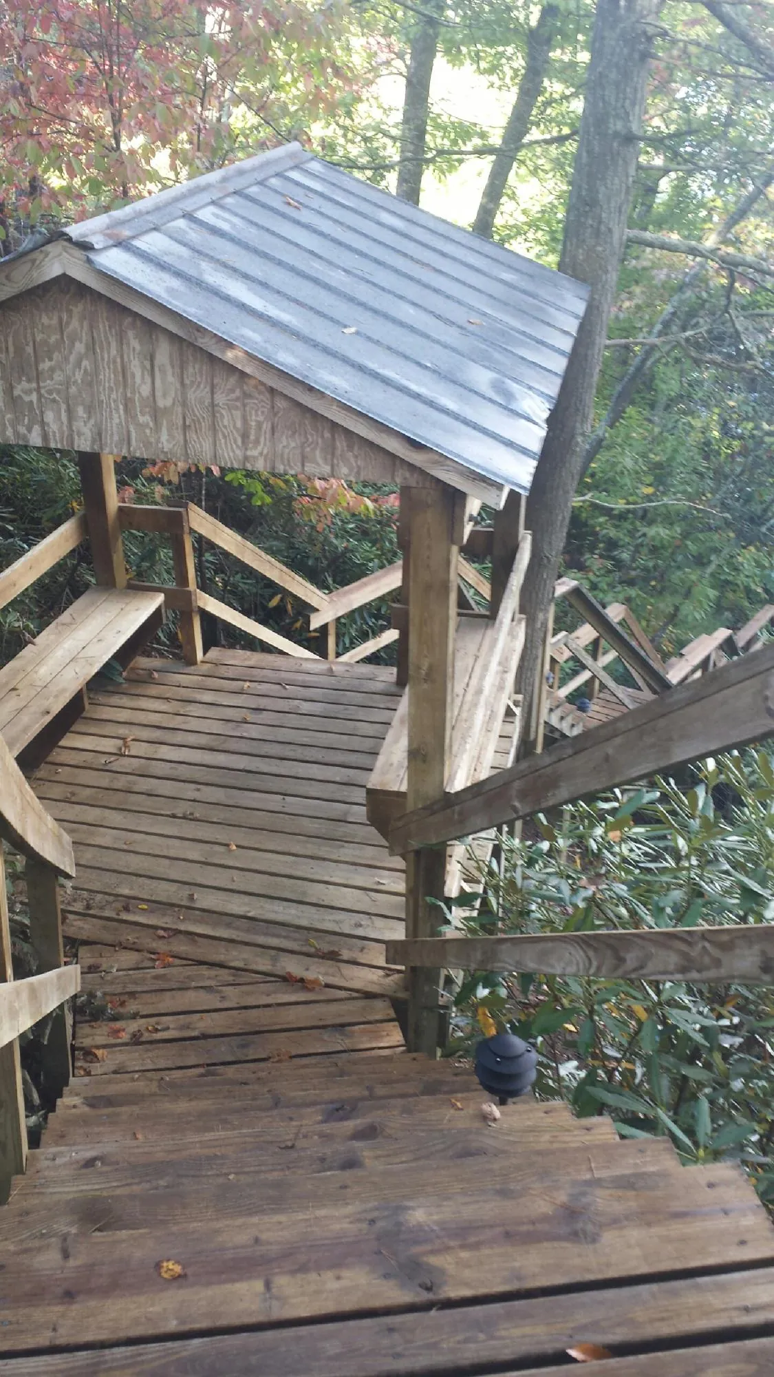 Metal roofed shelter over wooden steps on a wooded walkway — Skylight Repair & Installation work by our crew in Monponsett