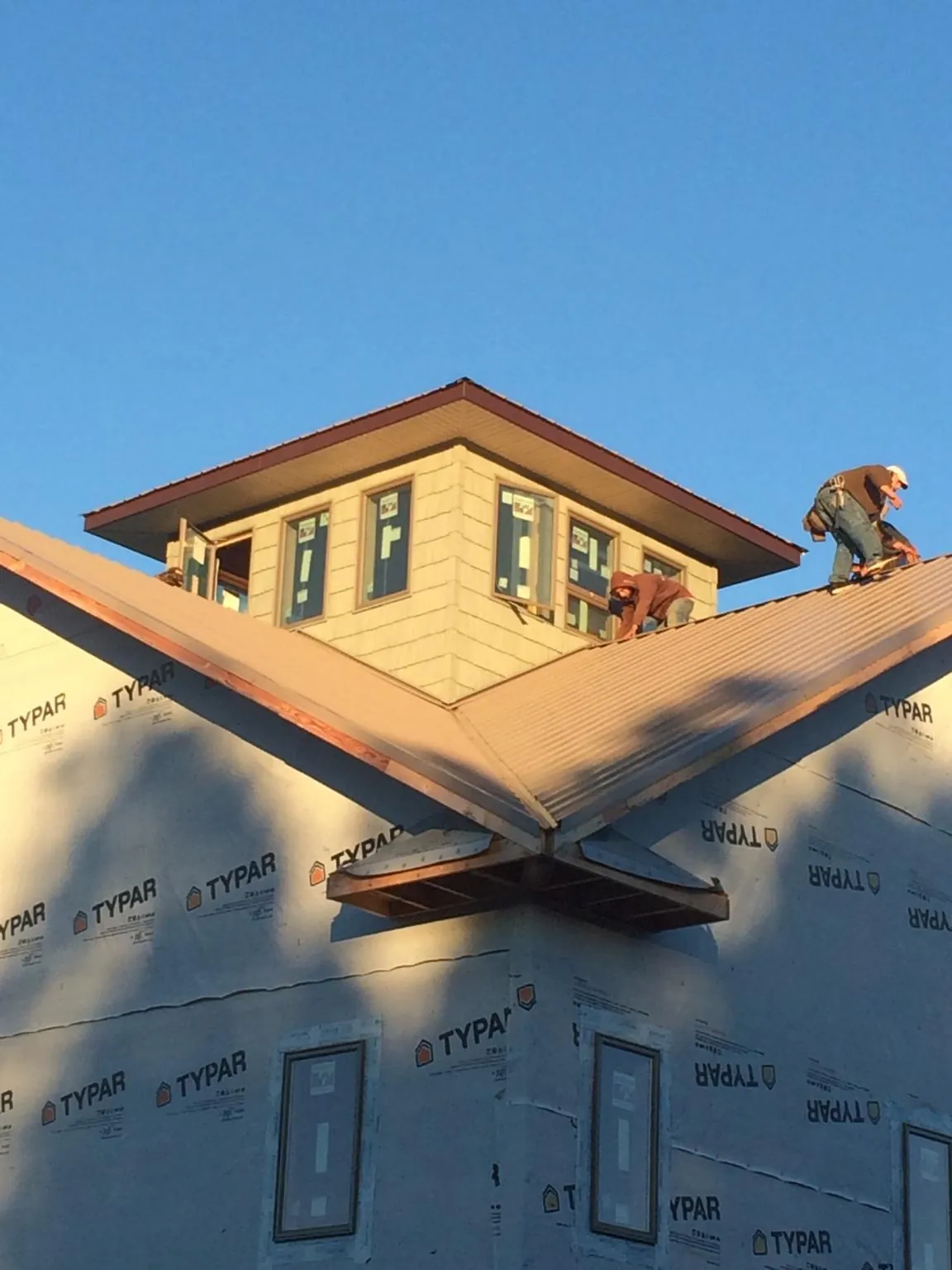 Roofers working around a rooftop cupola on a new metal roof at sunset — Roof Waterproofing in Monponsett by Roofing Brothers